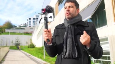 Şık kış kıyafetleri içinde yetişkin bir erkek vlogger şehirde online video kaydediyor.