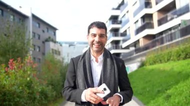 Mutlu iş adamı, neşeli bir sonbahar gününde şehrin dışında cep telefonuyla kutlama yaparken dans ediyor.