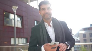 İş adamı elinde akıllı bir telefonla şehirde dans edip kutlama yapıyor.