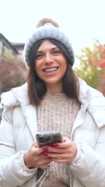 Güneşli bir sonbahar gününde dışarıda cep telefonu kullanan düşünceli bir kadın.