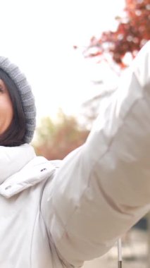 Kışın şehirde cep telefonuyla selfie çeken beyaz bir kadın.