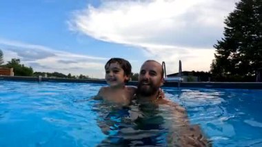 Baba ve küçük oğlu evlerinin arka bahçesindeki bir yüzme havuzunda oyun oynuyorlar.