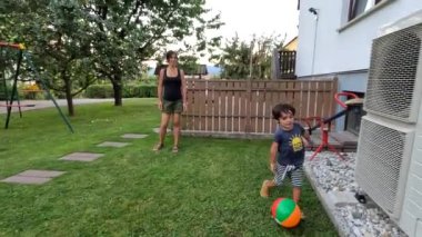 Anne ve küçük oğlu evlerinin arka bahçesinde top oynayarak birlikte güzel vakit geçiriyorlar.