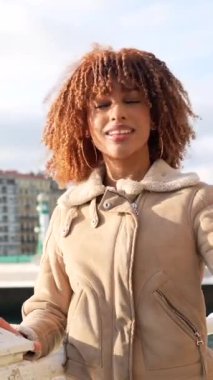 Güzel bayan Latin gezgin şehirdeki bir nehrin yanında telefonla kayıt yapıyor.