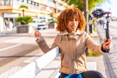 Milenyum içeriği yaratıcısı Latin genç bir kadın şehirde internette vlog yapıyor.