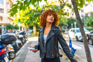 Bin yıllık Latin bir kadının kenarda yürürken müzik dinlemesinin yan görüntüsü.