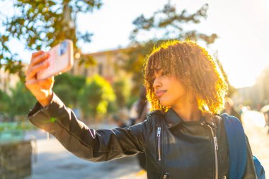 Güzel, havalı Latin bir kadının gün batımında selfie çekerken görüntüsü.