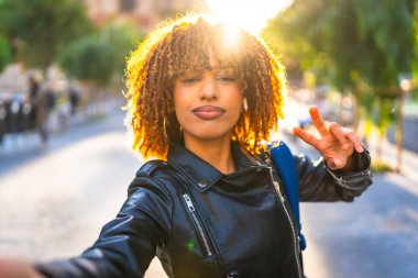Gün batımında sokakta selfie çekerken başarılı olan Latin bir genç kadın turist kişisel bakış açısı