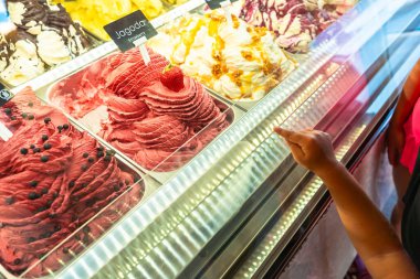 Çocuk Adriyatik kıyısındaki yaz tatillerinde Piran, Slovana 'da bir gelateria' da çilekli dondurmaya işaret ediyor.