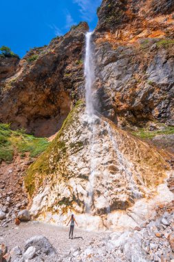 Female hiker admiring the stunning view of rinka waterfall cascading down a rocky cliff in logarska dolina, slovenia clipart