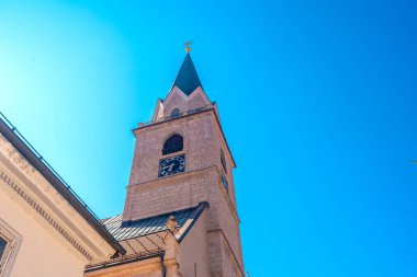 Bir kilise kulesinin alçak açılı görüntüsü Kranj, Slovenia 'daki canlı mavi gökyüzüne karşı, şehrin mimari cazibesini sergiliyor.