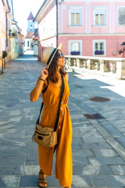 Genç bir kadın turist güneşli bir yaz gününde Kranj, Slovenia 'nın büyüleyici sokaklarını keşfediyor.