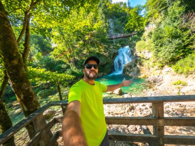 Selfie çeken ve güzel Tolmin vadilerini gösteren bir turist yaz tatilinde Slovenia 'da şelaleler açıyor.