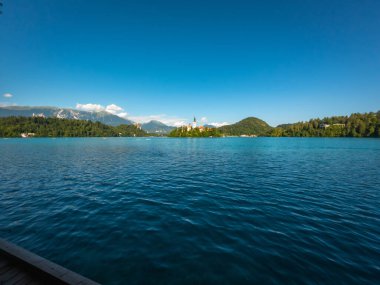 Sakin göl manzarası, sakin mavi sular ve berrak bir gökyüzü ile çevrili, kanayan adada Maria 'nın varsayımının hac kilisesi ile birlikte kanadı.
