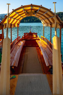 Çizgili gölgelikli ahşap pletna tekne ve kürekler Julian Alplerinde kanayan turistleri bekliyor, Slovenia, popüler bir yaz tatili beldesi.