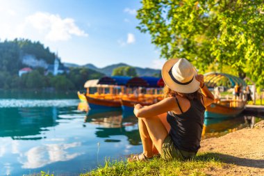 Hasır şapkalı genç bir kadın gölün kenarında otururken kanaması vardı. Geleneksel Pletna teknelerine hayranlık duyuyordu. Meryem Kilisesi 'nin varlığına inanıyordu.