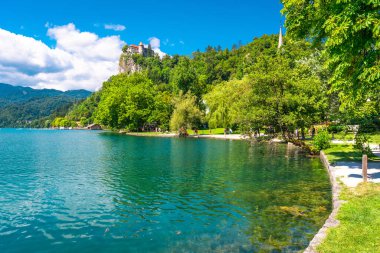 Yaz tatilinin tadını çıkaran turistler gölün manzaralı kıyılarında kanayan bir şatoyla Julian Alpleri 'ndeki bir uçurumun tepesine tünediler.