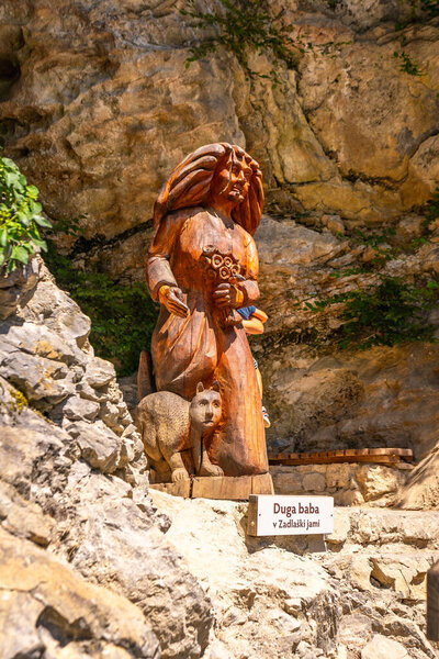 Деревянная скульптура, изображающая бабу, мифологическое существо, держащее цветы в сопровождении медвежонка, расположенного в ущельях толмин, Словения