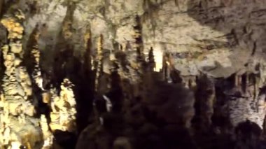 Turistler, post-jna mağarasının içindeki renkli ışıklarla aydınlatılan çarpıcı sarkıtlar ve dikitler karşısında hayrete düşüyorlar.