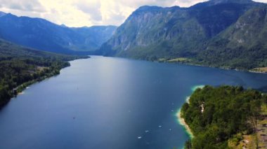Serene tekneleri, çarpıcı bir yaz gününde Slovenia 'daki Bohinj gölünün sakin sularında süzülür.