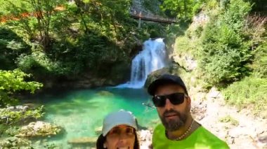 Şelale ve ahşap köprüyle selfie çeken turistler Tolmin Vadisi, Triglav Ulusal Parkı 'nın arka planında