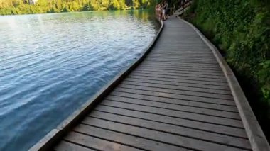 Işıl ışıl bir yaz gününde, bereketli yeşilliklerle çerçevelenmiş ikonik kilisesiyle gölün kanayan adasının sakin manzarası.