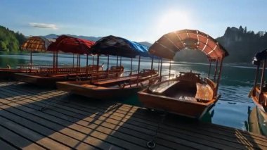 Pletnas olarak bilinen ahşap turist tekneleri, göldeki bir rıhtımda demirlediler, Slovenia 'da kanları aktı, güneşin altın ışığında yıkandılar.