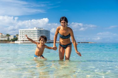 Anne ve oğul Mallorca, İspanya 'daki sığ ve berrak Estanys sahillerinde el ele tutuşup eğleniyorlar.