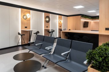 Birkaç sandalye ve saksı bitkisi olan bir bekleme odası. Sandalyeler siyah, saksı bitkisi yeşil.