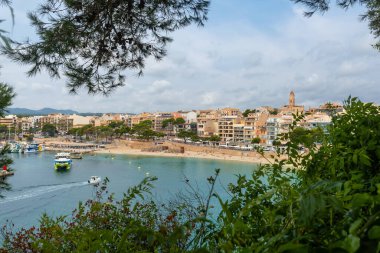Porto Cristo 'nun turkuaz sularında yüzen tekneler, canlı bir Akdeniz şehir manzarası ve yemyeşil bitki örtüsüyle