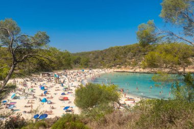 Turistler, Mallorca, İspanya 'daki Cala s' amarador sahilinin güzel turkuaz sularında dinleniyor ve yüzüyorlar.