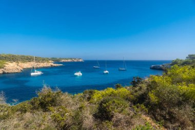 Lüks yelkenliler ve yatlar, güneşli bir yaz gününde Cala Mondrago doğal parkında, Mallorca, İspanya 'daki güzel bir körfezin turkuaz sularında dinleniyor.