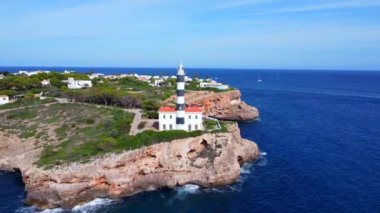 Portocolom deniz feneri, Akdeniz 'de yol alan gemiler için güvenli bir yol gösterici olan Mallorca' nın engebeli sahilinde dimdik ayakta duruyor.