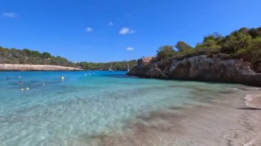 Turkuaz su, turistlerin yüzdüğü ve güneşlendiği Mallorca adasındaki güzel bir koyda parıldıyor.