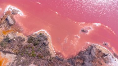 Torrevieja 'daki pembe gölün havadan görünüşü gün batımında güneş ışığını yansıtıyor, canlı renkleri vurguluyor ve İspanya' da yakınlardaki tuz madenini vurguluyor.