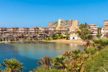 La manga del mar 'daki sakin yaz sahnesinde sakin Akdeniz sularına yansıyan binalar, Cala del Pino