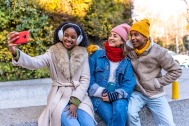 Üç arkadaş kışın şehirde selfie çekiyorlar, birlikte vakit geçiriyorlar.