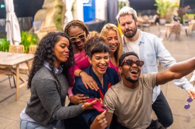 Gece partisinde bir barın terasında selfie çeken bir grup çok ırklı arkadaş.