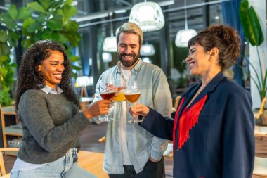 Çok ırklı üç mutlu arkadaş bir gece barının terasında kutlama yapıyor.