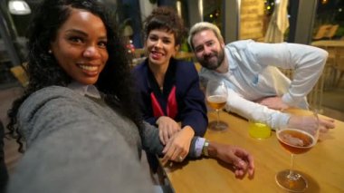 Latin kadın ve arkadaşları barda oturup bira içerken selfie çekiyorlar.