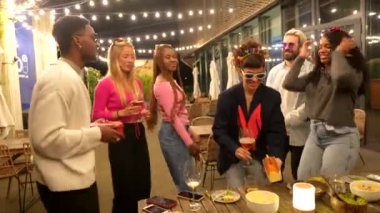 Çok ırklı arkadaşlar, gece yarısı barda doğum günü pastası ile sürpriz yapan bir kadın.