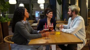 Çoklu etnik çeşitlilikteki iş arkadaşları işten sonra bir barın önünde birlikte bira içiyorlar.