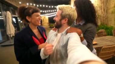 Mutlu çoklu etnik çeşitlilikte genç arkadaşlar gece partisinde balkonda selfie çekiyorlar.