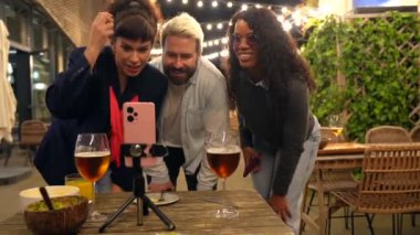 Bir bar terasında gece partisinde telefon görüşmesi yapan çeşitli arkadaşlar.