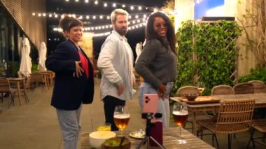 Bir şehir barının terasında gece partisinde birlikte dans ederken çok ahlaklı arkadaşlar koreografi yapıyor.