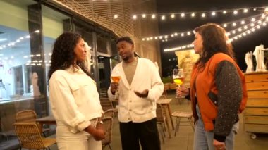 İşten sonra terasta bira içerken çok ırklı iş arkadaşları konuşuyor.