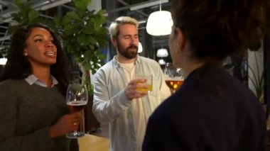 Çok ırklı arkadaşlar kadeh kaldırıyor ve bir bar terasında gece partisinin başarısına kadeh kaldırıyorlar.