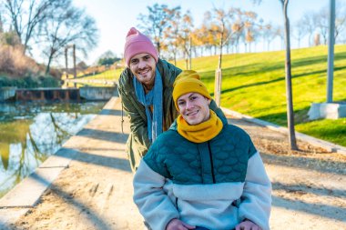 Parkta güneşli bir günün keyfini çıkaran iki arkadaş engelli insanlara destek ve destek veriyor.