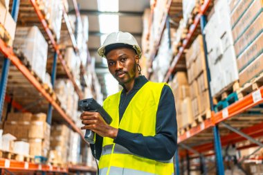 Bir depoda paketleri tararken kameraya bakan Afrikalı bir erkek işçinin portresi