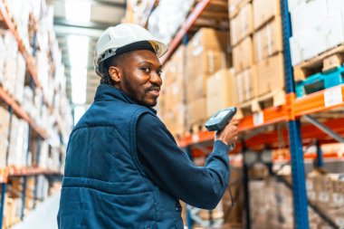 Büyük bir depoda paketleri tararken mutlu Afrikalı işçiler gülümsüyor.